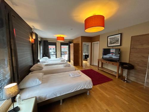 弗朗科尔尚拉斯客房旅馆的一间设有三张床和电视的房间