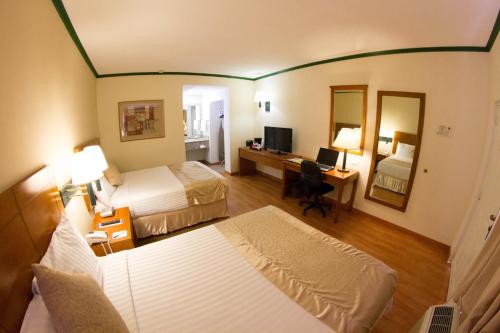 蒙克洛瓦Hotel Las Misiones的酒店客房设有两张床和一张带电脑的书桌