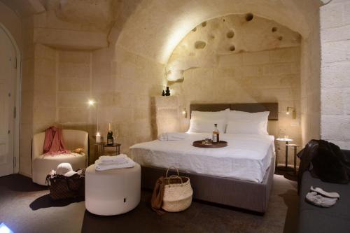 马泰拉Le Malve Cave Retreat的一间卧室配有一张大床和一把椅子