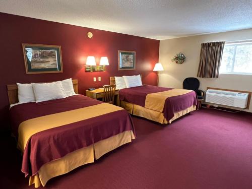 EmmetsburgAmericas Best Value Inn Suburban的红色墙壁的酒店客房内的两张床
