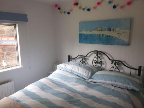 BursledonRockets's Retreat的一张带蓝色和白色毯子的床和一个窗口