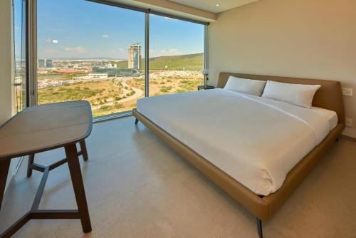 克雷塔罗Park Life Querétaro的一间卧室配有一张床、一张书桌和一个大窗户