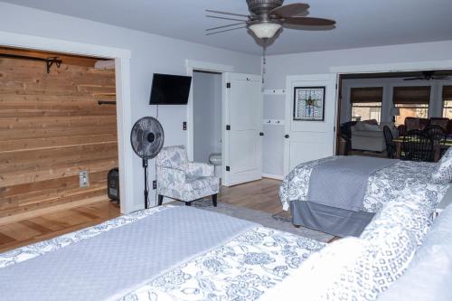 The Retreat by On Cue Properties的一间卧室配有两张床、风扇和椅子
