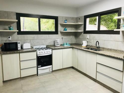 卢汉德库约Hermosa casa con Jacuzzi y sauna en Chacras de Coria的厨房配有白色橱柜和炉灶烤箱。