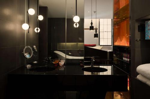 悉尼悉尼QT精品酒店的黑色浴室设有两个盥洗盆和镜子