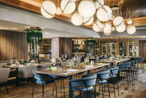 基茨比厄尔Grand Tirolia Kitzbühel - Member of Hommage Luxury Hotels Collection的餐厅设有长桌、椅子和大吊灯。