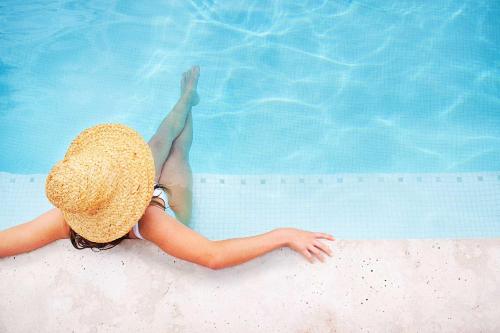 莫里莫科Bannisters Pavilion Mollymook的躺在游泳池边的稻草帽上的女人