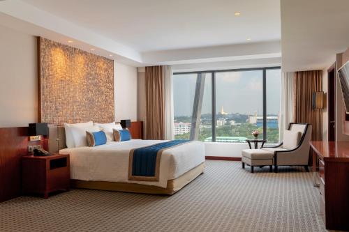 仰光Yangon Thanlwin Hotel的酒店客房设有一张床和一个大窗户