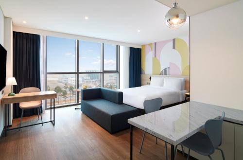仁川市ibis Styles Ambassador Incheon Airport T2的酒店客房配有床、沙发和桌子。