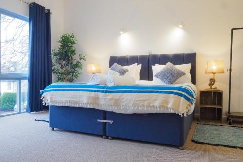 Budock WaterCoverack的一间卧室配有蓝色的床和白色枕头