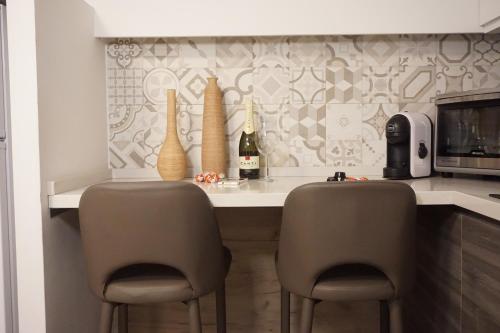 卡塔尼亚Catanese Proverb's House - Via Napoli的厨房配有带2把椅子的柜台和1张带葡萄酒瓶的桌子。