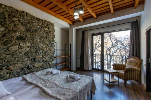 梅斯蒂亚Mestia Hotel Amirani的一间卧室设有石墙、一张床和一把椅子