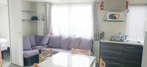 莱马特Camping Siblu les Charmettes的一间带紫色沙发的客厅和一间厨房