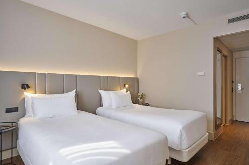 克尔斯特尔巴赫NH法兰克福机场酒店的配有白色枕头的酒店客房内的两张床