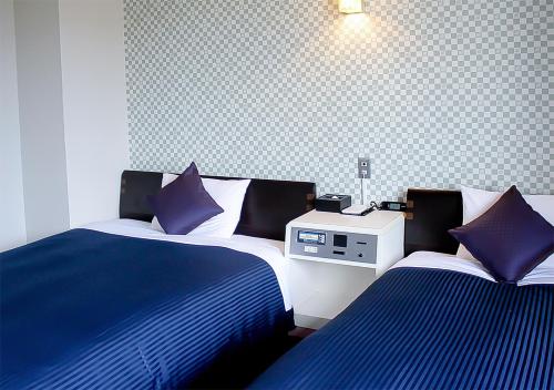 UchinadaHotel Livemax BUDGET Kanazawa-Idaimae的一间卧室配有两张带蓝白色床单的床
