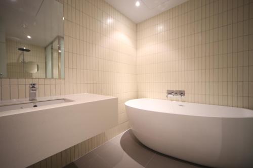 釜山Hound Hotel Junggwan的白色的浴室设有浴缸和水槽。