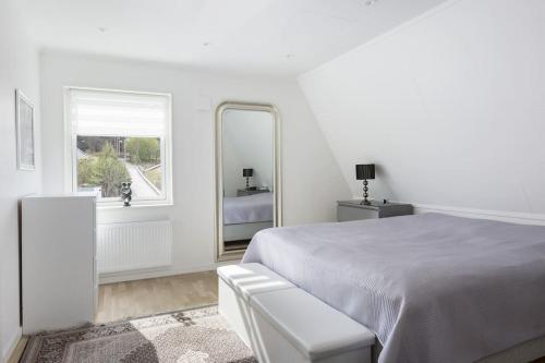 哥德堡Modernt hus med parkeringsplatser och trädgård的白色卧室配有床和镜子