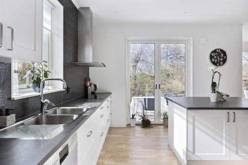 哥德堡Modernt hus med parkeringsplatser och trädgård的白色的厨房设有水槽和窗户