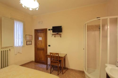 佛罗伦萨玛格丽特酒店的卧室配有书桌和墙上的电视。