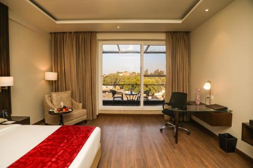 占西Regenta Place Jhansi by Royal Orchid Hotels Limited的配有一张床、一张书桌和一扇窗户的酒店客房