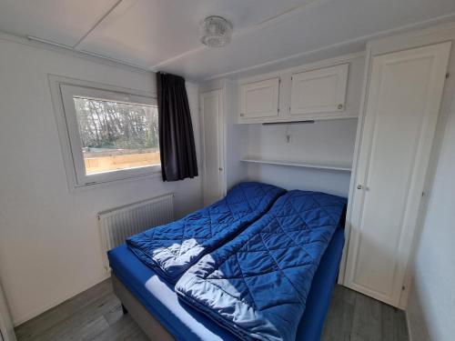 德科赫Chalet Texel DREaM nr. 17 op Chaletpark Bregkoog的一间小卧室,配有一张蓝色的床和窗户