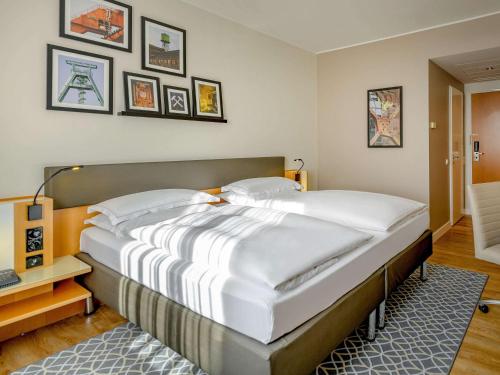 波鸿波鸿市美居酒店的卧室内的一张大床,墙上挂着照片