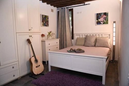 威尼斯Grace Apartment in Venice的卧室配有白色的床和吉他