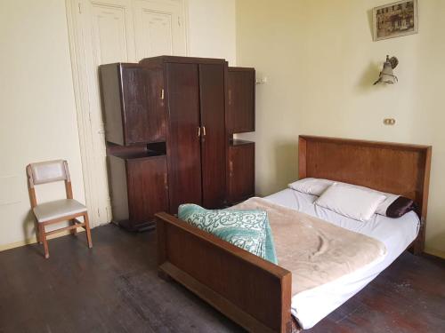 亚历山大Clement's House Hostel的一间卧室配有一张床、一个橱柜和一把椅子