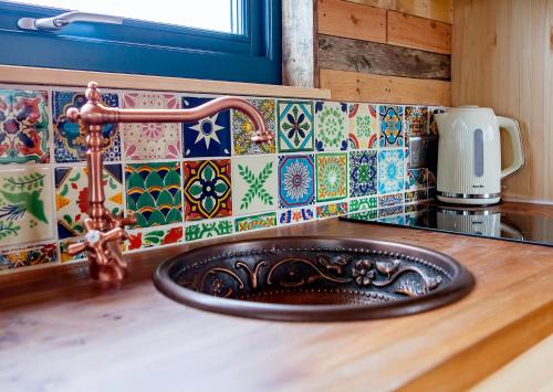 科比Laundimer House的厨房里的一个水槽,有色彩缤纷的瓷砖