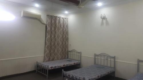 拉合尔Residency Girls Hostel - For Females Only的配有窗帘的客房内的两张单人床