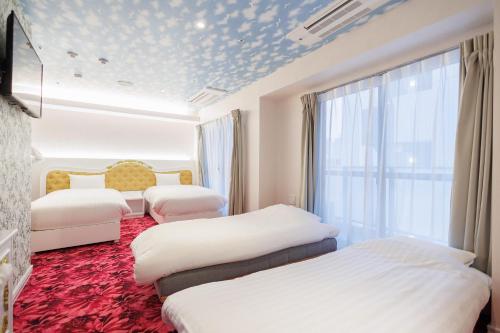 东京Hotaku HOTEL Akihabara的酒店客房设有三张床和窗户。