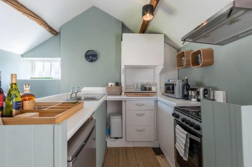 赛伦塞斯特Talliers Cottage - Characterful & Central的厨房配有白色橱柜和炉灶烤箱。