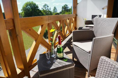 DrahnsdorfFeWo-Zimmer-Auszeit的阳台配有两把椅子和一张带酒瓶的桌子