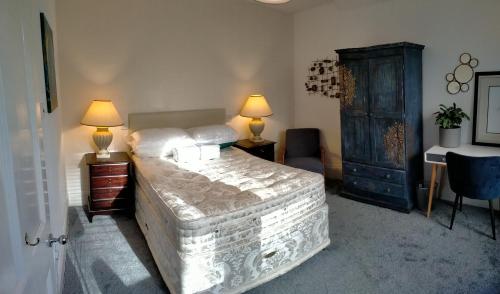 伦敦1 Bed flat in East Dulwich的一间卧室配有一张床、两盏灯和一张书桌。