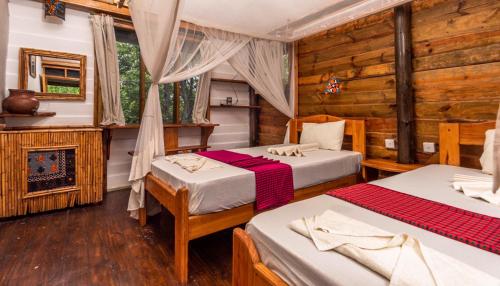 SaadaniMiseni Retreat的一间卧室设有两张床和一个壁炉