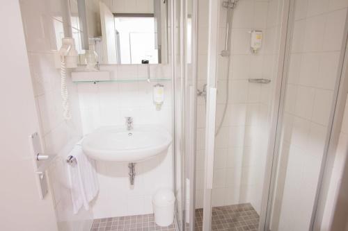 美因河畔法兰克福塞内特酒店的白色的浴室设有水槽和淋浴。