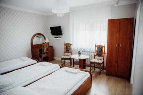 MławkaPokoje gościnne Biała Dama的一间卧室配有两张床、一张桌子和一台电视。