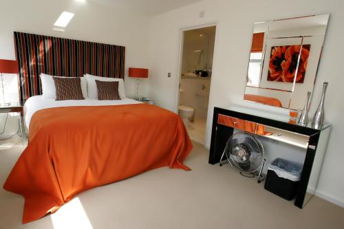 切姆切姆斯福德服务式公寓酒店的一间卧室配有一张带橙色毯子和壁炉的床