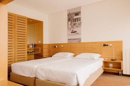 埃斯波森迪Parque do Rio Ofir Hotel的一间卧室配有一张大床和木制床头板