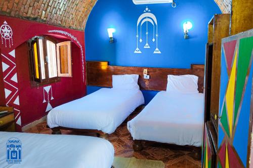 阿斯旺Kato Waidi Nubian Resort的配有两张床铺的蓝色和红色墙壁客房