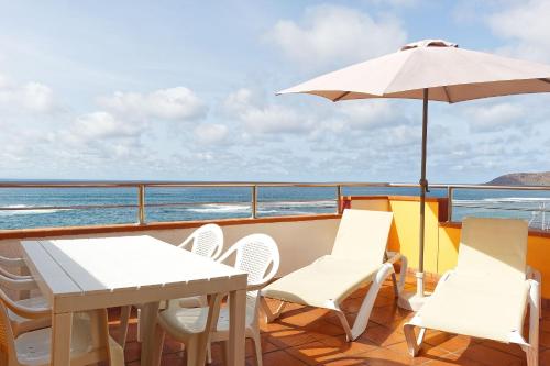 大加那利岛拉斯帕尔马斯梅普康缇瑞斯公寓酒店的阳台配有桌椅和遮阳伞。