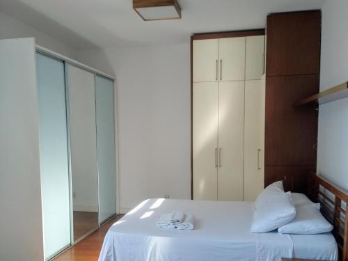 里约热内卢Luna Rossa Guest House的一间卧室配有一张带白色床单和镜子的床