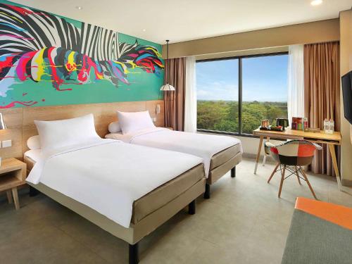 茂物茂物拉亚宜必思风格酒店的酒店客房设有两张床、一张书桌和一个窗户。