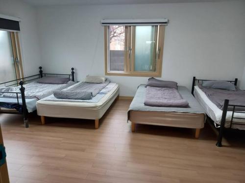 济州市Summer's House的带三张床和窗户的客房