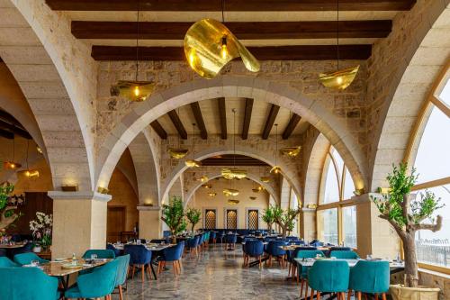 乌奇希萨尔磨石山洞套房酒店的一个带桌子和蓝色椅子的用餐大厅
