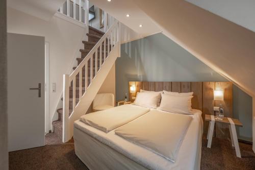 蒂门多弗施特兰德SAND Lifestylehotel的一间卧室设有一张床和一个楼梯