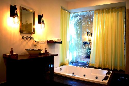 加尔加Paatlidun Safari Lodge, Jim Corbett的带浴缸、窗户和水槽的浴室