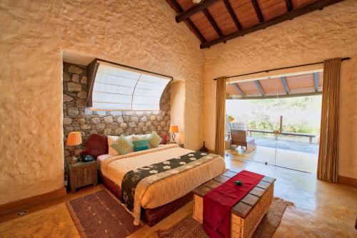 加尔加Paatlidun Safari Lodge, Jim Corbett的一间卧室设有一张床和一个大窗户