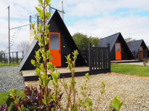 利马瓦迪Carrowmena Family Glamping Site & Activity Centre的一座带橙色门和黑色屋顶的房子