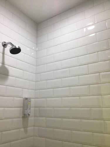 万隆Bandung Hostel的一间铺有白色瓷砖墙的浴室和淋浴